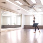 Une ballerine en tutu noir s'exerce à la danse classique dans un studio lumineux avec de grands miroirs