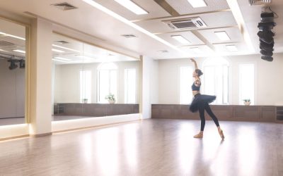 Une ballerine en tutu noir s'exerce à la danse classique dans un studio lumineux avec de grands miroirs