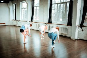 Trois jeunes femmes pratiquent la danse contemporaine lors d'une répétition dans un loft industriel